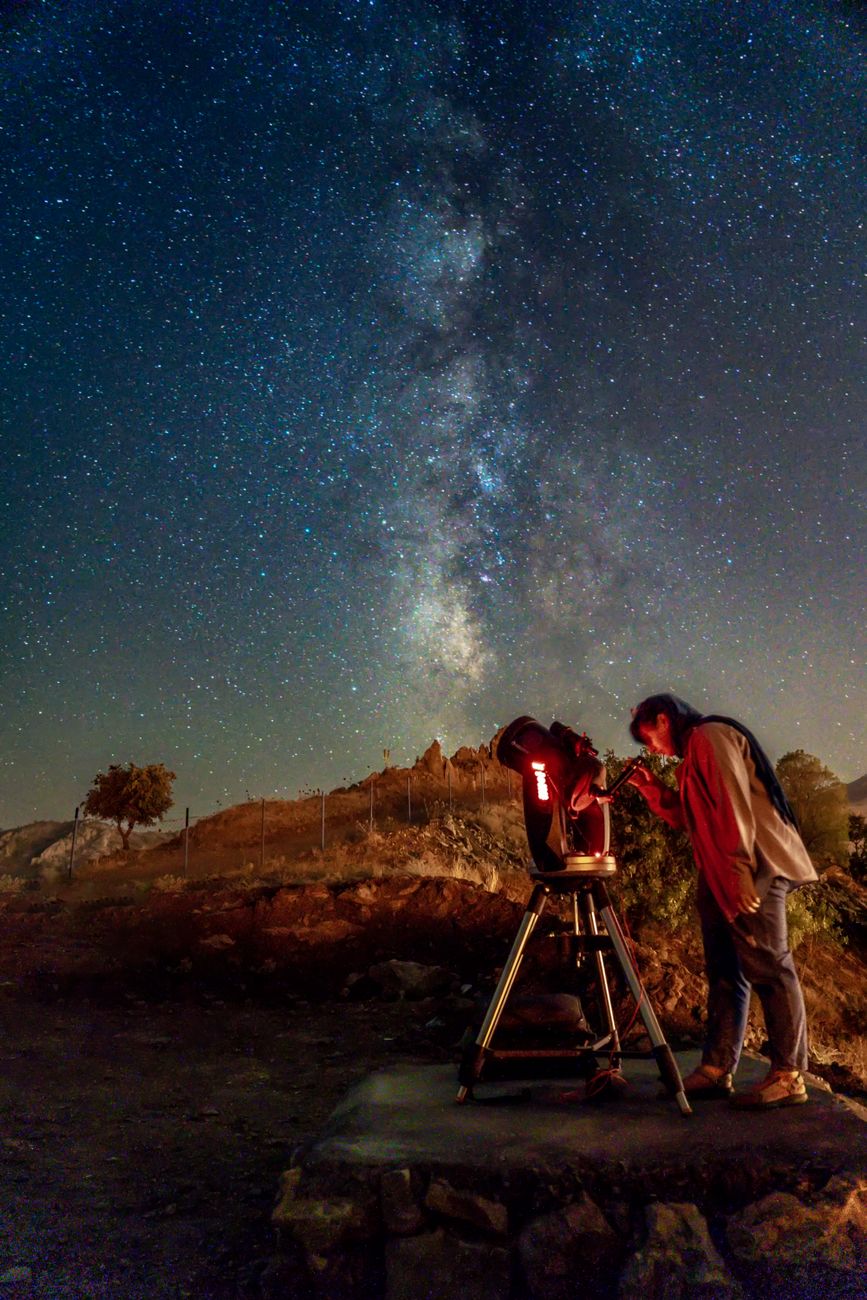 A person observes the night sky with a telescope under stars in Kermanshah, Iran.